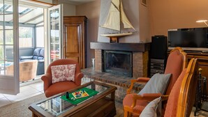 A living room with a fireplace, a sailboat decoration, and a television. - Ty Louarn 1 by Interhome (Kerlouan)