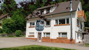 Ein zweigeschossiges Gebäude mit einer großen Wandmalerei an der Vorderseite, einer Ziegelbasis und mehreren Fenstern.