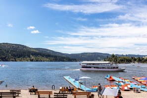 A lakeside view with a boat, wooden benches, and colorful umbrellas.