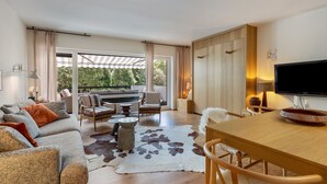 Una sala de estar moderna con sofá, sillas, mesa de comedor y televisor.