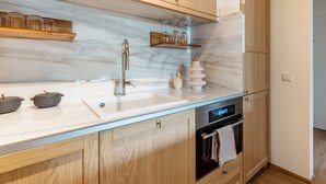 Una cocina moderna con armarios de madera, encimera de mármol, horno empotrado y un reloj digital.