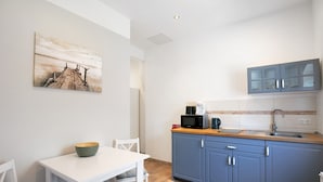 Eine moderne Küche mit einem weißen Tisch, blauen Schränken und einem Gemälde an der Wand.