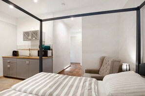 A modern hotel room with a bed, a chair, a desk with a computer, and a kitchen area. - Studio Apartment 'Apartment 3 - Koppel' with Shared Terrace and Wi-Fi (Ludwigsfelde)