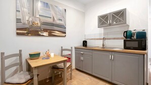 Una cocina con gabinetes grises, una mesa de madera, una silla, un cuadro y un microondas.
