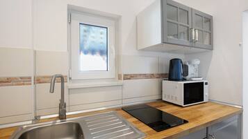 A modern kitchen with a stainless steel sink, a window, a microwave, and a built-in oven.