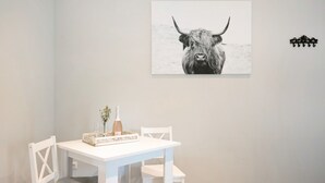 Une table blanche sur laquelle se trouvent un cadre avec une photo d  ’un taureau, une bouteille et des verres.