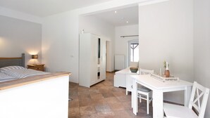 Une chambre à coucher avec un lit, une table de chevet, une lampe et une armoire blanche.