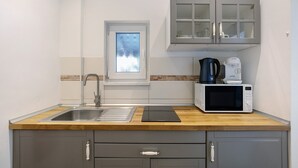 Une cuisine compacte équipée d’un évier, d’un four à micro-ondes et d’une machine à café.