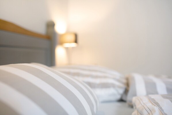 A bed with striped bedding and a wall-mounted lamp.