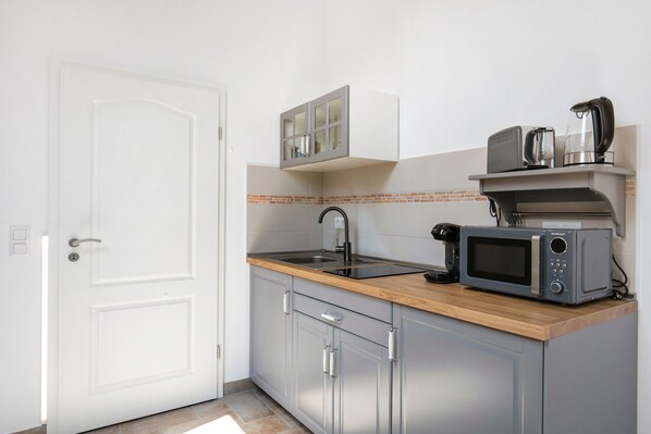 A compact kitchen with a microwave, kettle, and a small sink.