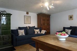 Un salon avec une table en bois, deux canapés bleu foncé, un meuble vert et une carte accrochée au mur.