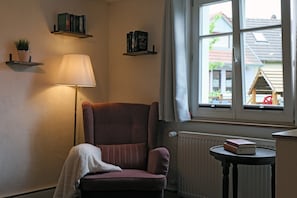 Une pièce avec une chaise, une lampe, une fenêtre et un radiateur.
