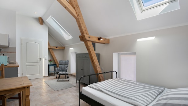 Un dormitorio con tragaluz, cama, escritorio y silla.