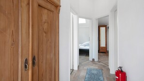 A hallway with a wooden wardrobe, a bed in the background, and a red fire extinguisher. - Studio Apartment 'Apartment 7 - Nuthefließ' with Shared Terrace and Wi-Fi (Ludwigsfelde)