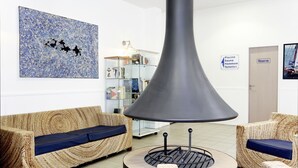 Un interior moderno con una zona de estar circular, un cuadro abstracto grande e indicaciones de servicios como piscina y sauna.