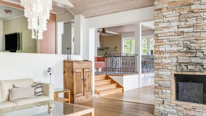 A spacious living area with a stone fireplace, a wooden cabinet, a glass coffee table, and a sofa.