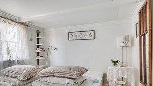 A neatly arranged bedroom with a bed, bedside table, lamp, and a framed quote on the wall.
