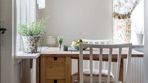 A wooden desk with a white chair, a potted plant, and a bowl of fruit.