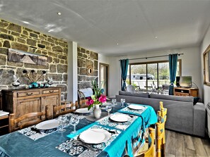 Enjoy meals in this beautifully set dining area with a long table, vase with flowers, and a stone wall.