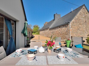 Enjoy al fresco dining in a serene outdoor setting with a table for four, surrounded by a stone wall.