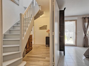 Staircase leads to an upper level, with a wooden cabinet and door to an outdoor area.