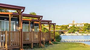 Een rij houten huisjes met balkons met uitzicht op een waterpartij en een brug op de achtergrond.