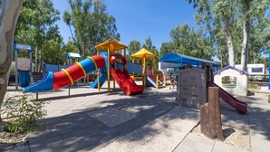 A playground with slides and climbing structures, surrounded by trees and a clear sky. - Camping Village Laguna Blu by Interhome (Alghero)