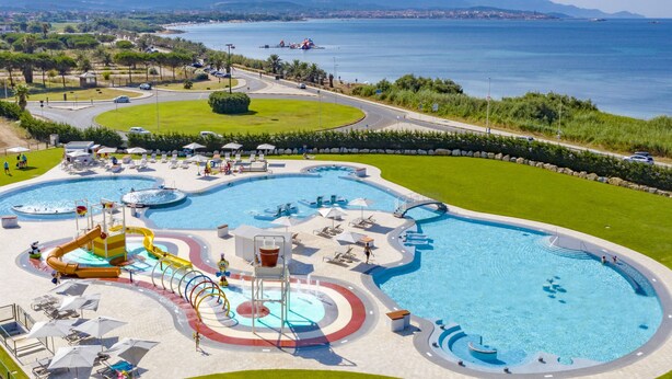 A large outdoor swimming pool with various water features and a surrounding area with lounge chairs and umbrellas. - Camping Village Laguna Blu by Interhome (Alghero)