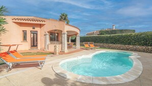 A pool area with lounge chairs and a stone wall. - Rei Sole (REI316) by Interhome (Costa Rei)