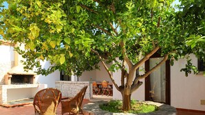 An outdoor patio with wicker furniture, a stone planter, and a brick floor. - Ville San Pietro (REI352) by Interhome (Costa Rei)