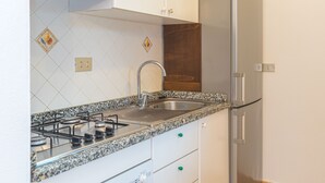 A kitchen with a gas stove, stainless steel sink, and a refrigerator. - Rei Sole Bilo (REI321) by Interhome (Costa Rei)