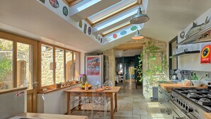 Une cuisine moderne dotée de fenêtres de toit, de murs en pierre et d’un coin repas avec des chaises transparentes.