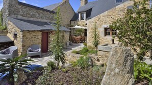 Un bâtiment en pierre doté d’un patio, d’un espace extérieur aménagé pour s’asseoir et d’une petite cascade décorative.