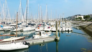 Un port de plaisance où de nombreux bateaux sont amarrés, l’eau est calme et le ciel est dégagé.