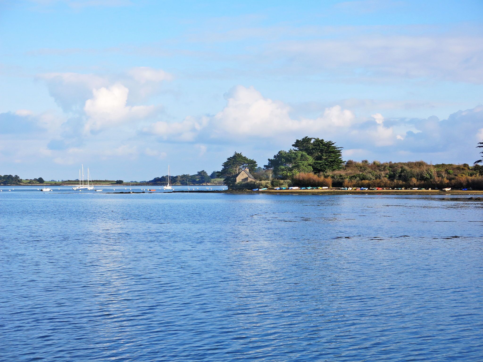 Un lago tranquilo con barcos y una orilla lejana.