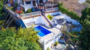 A large villa with a swimming pool, multiple balconies, and a garden.