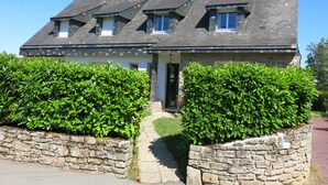 Ein zweistöckiges Haus mit Steinaußenwand, Ziegeldach und einer kleinen Veranda.