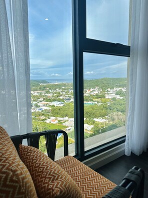 Ein Zimmer mit einem großen Fenster und Blick auf eine Stadt und Grünflächen.