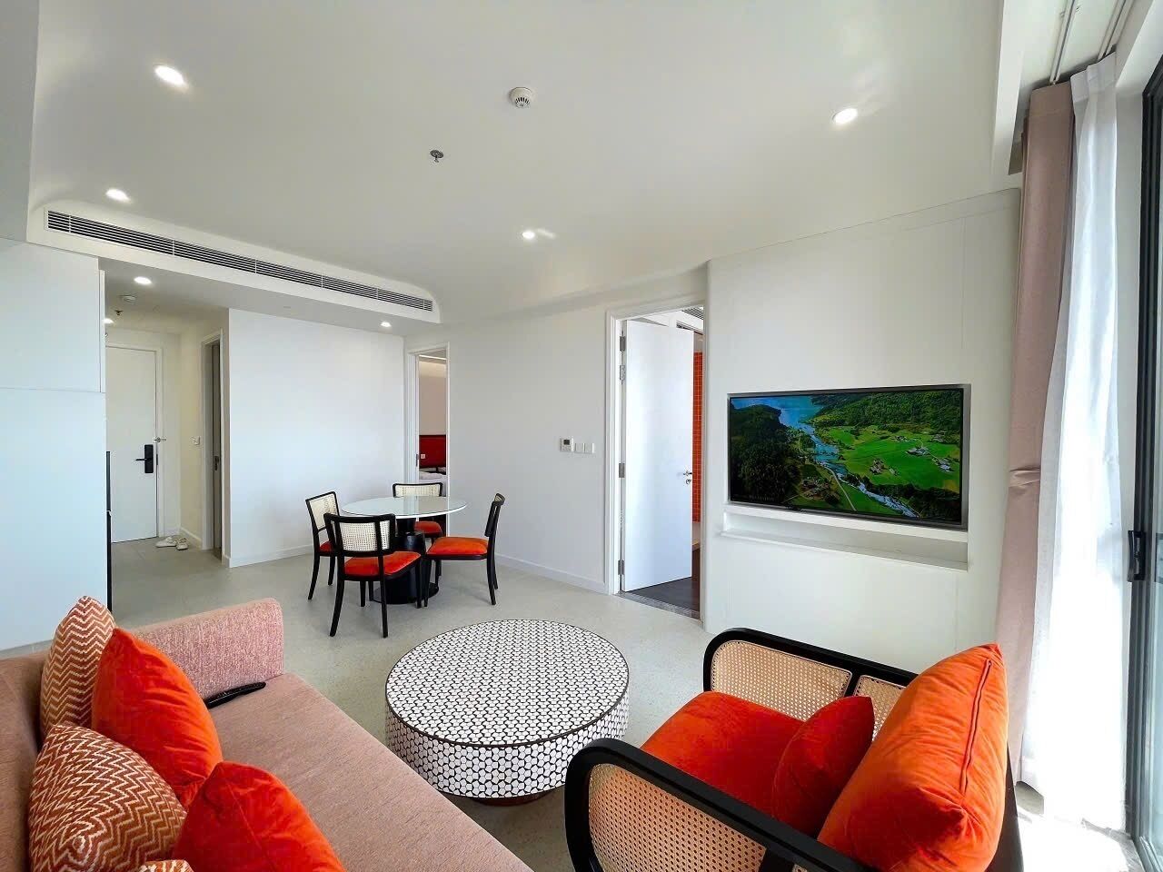 A modern living room with a sofa, ottoman, and dining table.
