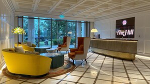 Een ruime lobby met een geruite vloer, een receptiebalie en een groot scherm waarop 