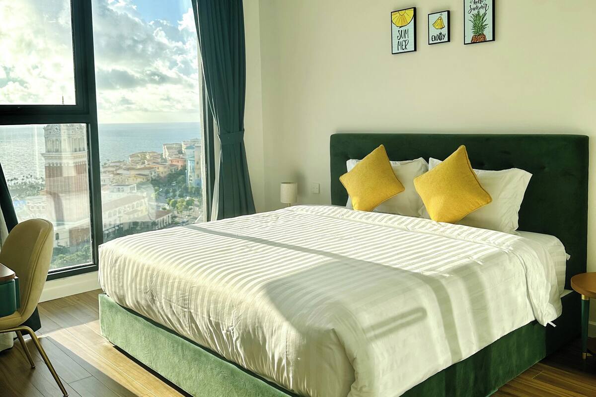 Une chambre d’hôtel moderne avec un grand lit, une vue sur la ville et un panorama urbain visible par la fenêtre.