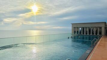 An infinity pool with a clear view of the ocean and a sunset.