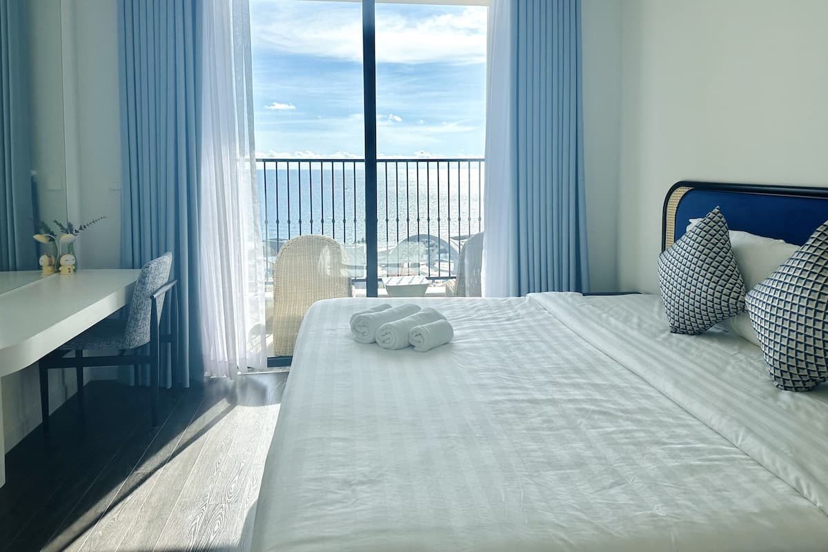 Une chambre d’hôtel avec un lit, un bureau et une vue sur la mer.