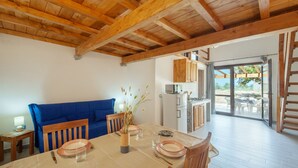 A dining area with a wooden table set for four, a blue sofa, and a kitchen in the background. - Loft la Pietraia by Interhome (Badesi)