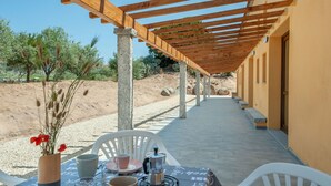 An outdoor patio with a pergola, stone pillars, and a table set for two with chairs. - Loft la Pietraia by Interhome (Badesi)