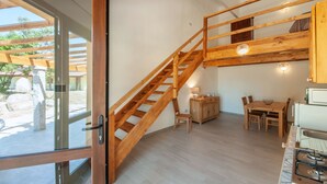 A modern kitchen with wooden flooring, a built-in stove, and a dining area with a table and chairs. - Loft la Pietraia by Interhome (Badesi)