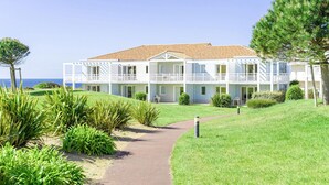 A two-story hotel with a red-tiled roof, multiple balconies, and a pathway leading to the entrance. - L'Estran (S4) by Interhome (Chateau d'Olonne)