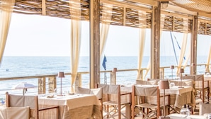 Un espace extérieur aménagé pour les repas, avec des tables et des chaises, offrant une vue sur la mer.