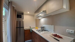 A modern kitchen with a stainless steel refrigerator, a microwave, a gas stove, and a sink. - Campeggio del Forte by Interhome (Marina di Bibbona)