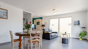 Ein modernes Wohnzimmer mit Essbereich, einer Couch, einem Fernseher und einer Topfpflanze.